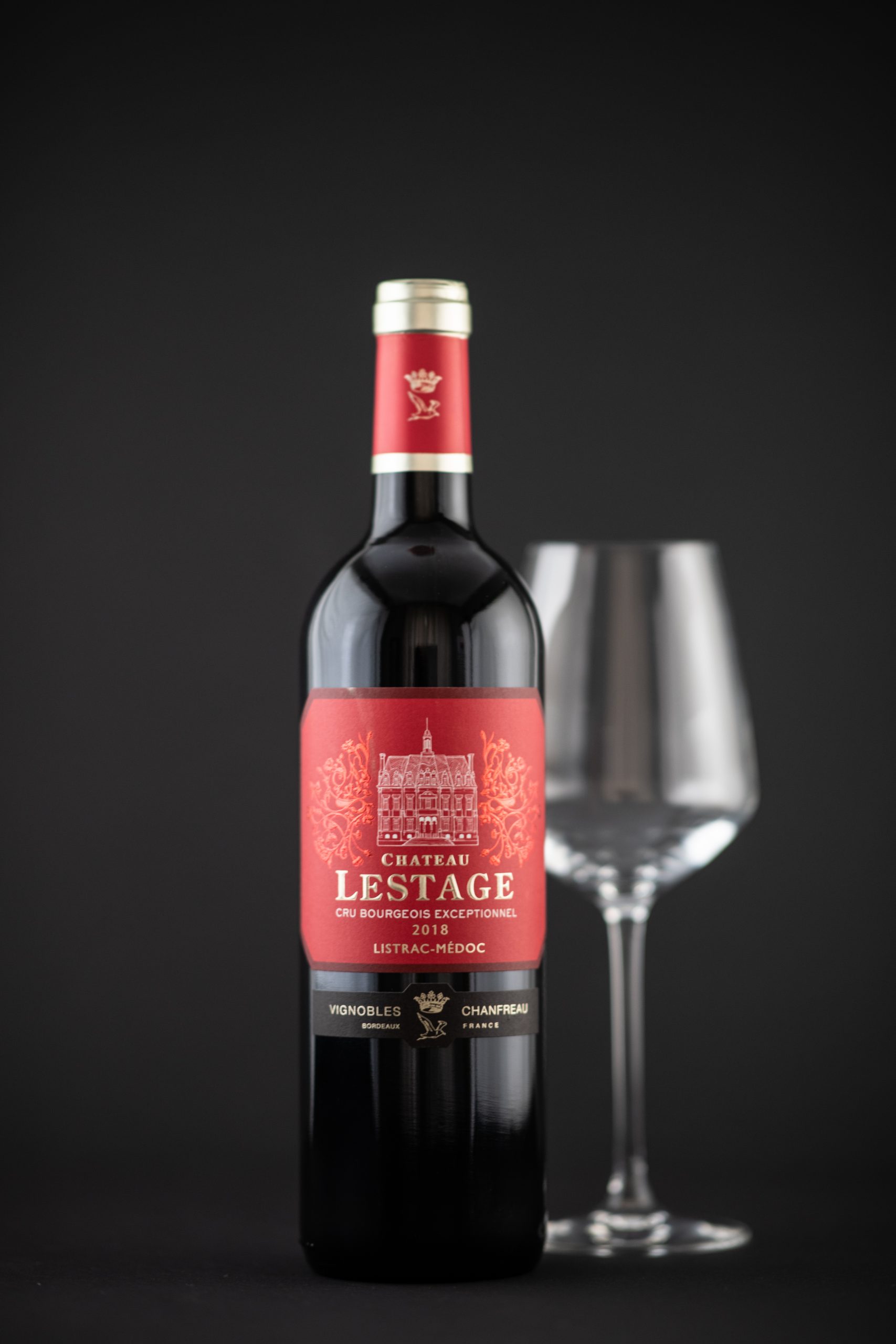 Photo d'une bouteille de vin rouge sur un fond noir avec un verre de vin