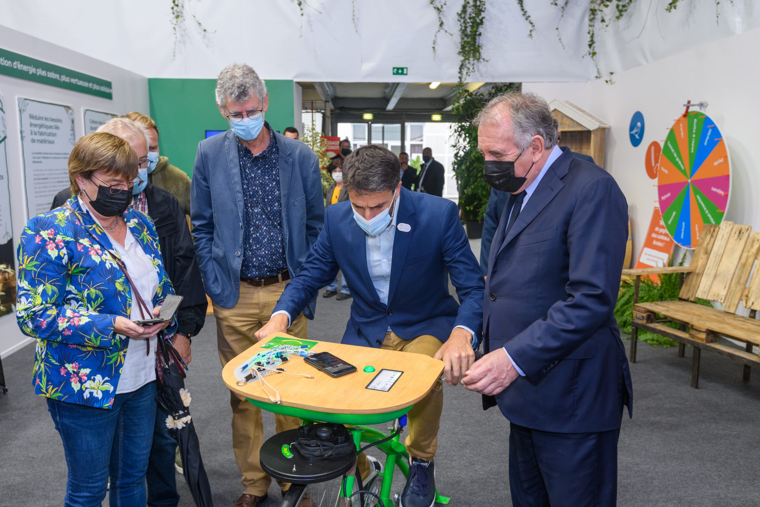 Tony Estanguet teste le chargeur de téléphone mobile à pédale (sur une base de vélo) en compagnie de François Bayrou, Maire de Pau, Haut commissaire au plan