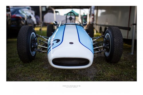 Vue de face d'un véhicule de course de collection bleu ciel et blanc dans son stand avant sa course au Grand Prix de Pau Historique
