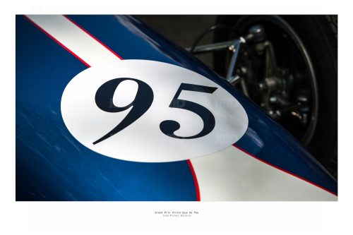 Vue  d'une face avant de véhicule de course de collection bleu foncé portant le numéro 95  dans son stand avant sa course au Grand Prix de Pau Historique