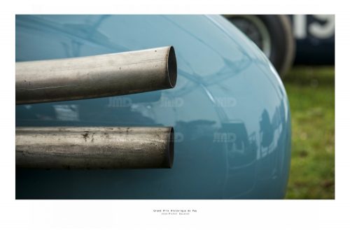 Vue arrière d'une voiture de course de collection bleue et ses échappements dans son stand avant sa course au Grand Prix de Pau Historique